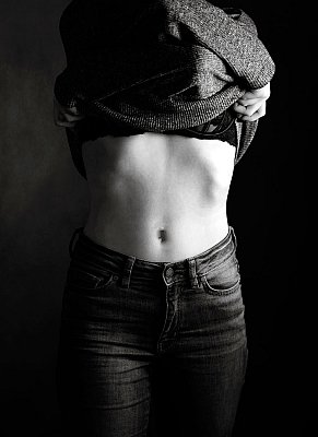 Boudoir portrait of a girl in jeans removing her top.