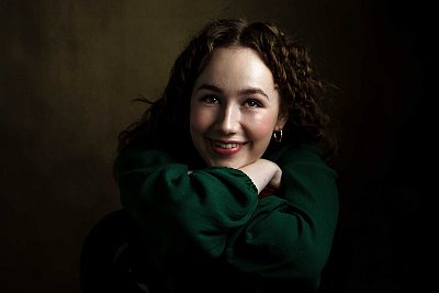 Studio portrait of young red head lady with a green dress.
