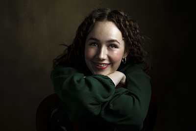 Studio portrait of young red head lady with a green dress.